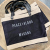a few market totes on a pile that has Peace + Aloha Makana on the tote
